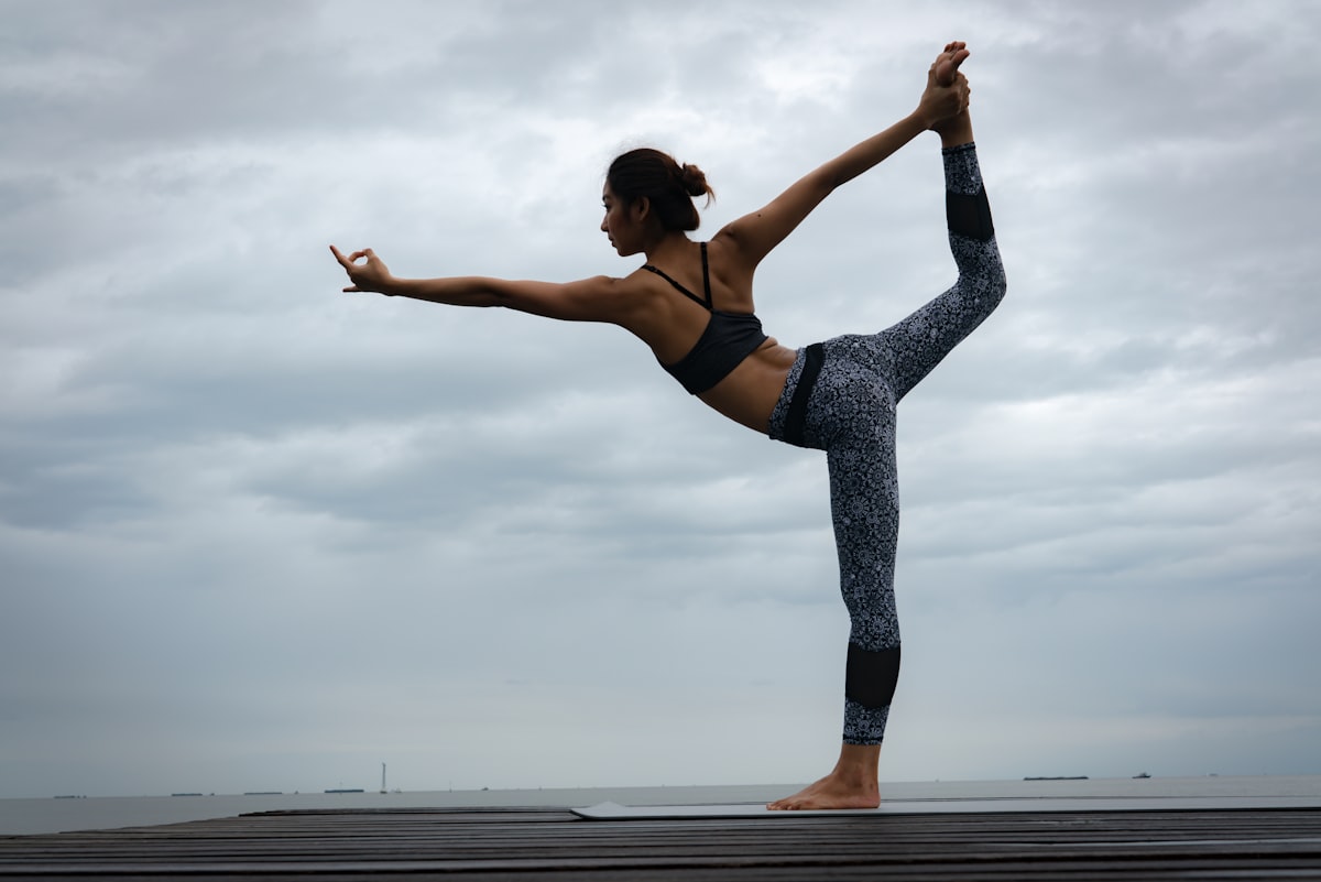 An athlete in patterned leggings holding a dancer's pose against the sky